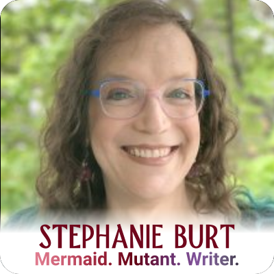 Stephanie Burt, a Jewish woman with shoulder-length, curly hair that is medium brown with teal tips, in a head-and-shoulders photo. She is wearing dangle earrings, trans-flag glasses that fade from blue to white to pink, and a black top with cut-outs. She is smiling at the camera. Headshot of Stephanie Burt, who is wearing glasses and smiling.
