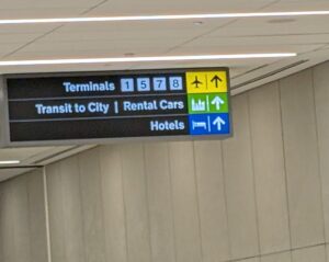 A sign pointing forward toward other terminals, transit to city and rental cars, and hotels.