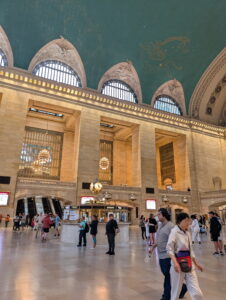 A photograph taken at Grand Central Terminal, on the street level, near the clock and information kiosk.